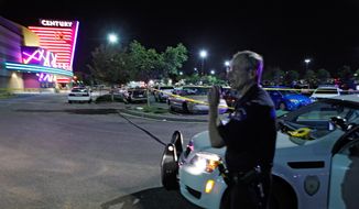 A police officer talks on his radio July 20, 2012, outside of the Century 16 theater at Aurora Mall in Aurora, Colo., where at least 14 people were killed and many injured at a shooting at the theater. (Associated Press)