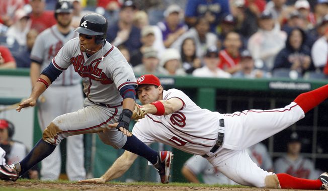 Atlanta Braves&#x27; Martin Prado, left, is run down on his way to the plate by Washington Nationals third baseman Ryan Zimmerman (11) during the eighth inning of the first baseball game of a doubleheader, Saturday, July 21, 2012, in Washington. The Braves won 4-0. (AP Photo/Carolyn Kaster)
