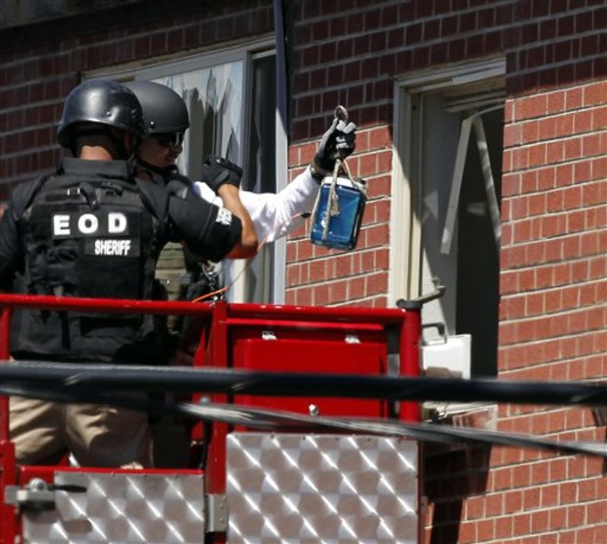 ** FILE ** Members of law enforcement wearing body armor and helmets prepare to what ATF sources describe as a "water shot" in the apartment of alleged gunman James Holmes Saturday, July 21, 2012 in Aurora, Colo. (AP Photo/Alex Brandon)