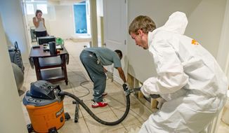 Technicians Dallas Jackson (center) and Ryan Watt, of ServePro, work to repair water damage in the basement of Kelly Ann Gray’s home in the Bloomingdale neighborhood caused by flooding after a downpour last week. (Andrew Harnik/The Washington Times)

