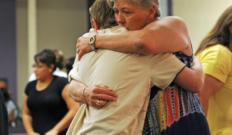 Joyce Young hugs her 13-year-old grandson, Justin Haynes, at the Restoration Christian Fellowship in Aurora on Sunday. Shooting suspect James Holmes, whose apartment also was booby-trapped with explosives, is slated to appear in court for the first time Monday. (Associated Press)