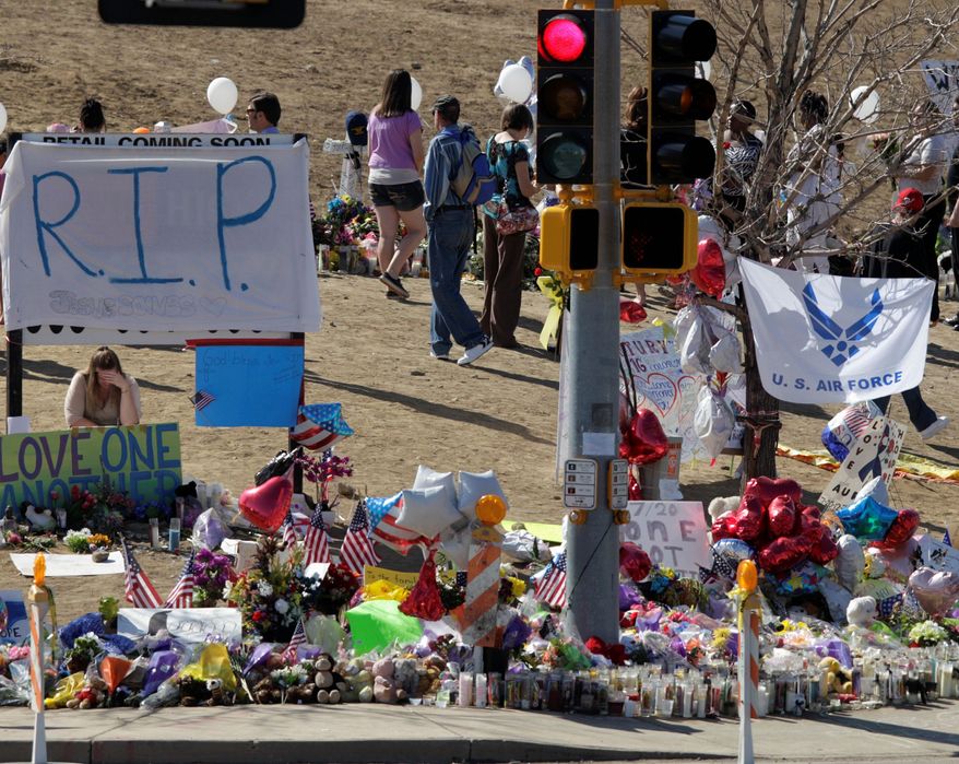 Throughout Tuesday, people bring flowers, candles, signs and other items to the growing memorial to the victims of Friday’s mass shootings in Aurora, Colo. The memorial, which is located across the street from the theater where 12 people were kiilled and scores others wounded. Colorado residents are bristling as their image of their state as a dangerous place to live. (Associated Press)