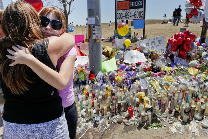 Stacy Fleming, 23, second from left, hugs her friend Pam Frakes Monday, July 23, 2012, at a make-shift memorial that the public created across the street from the Century Theater where a mass shooting occurred last Friday killing 12 and injuring dozens of others in Aurora, Colo. Fleming and her boyfriend decided to go to another theater to watch "The Dark Knight Rises" at the last minute. (AP Photo/Barry Gutierrez)