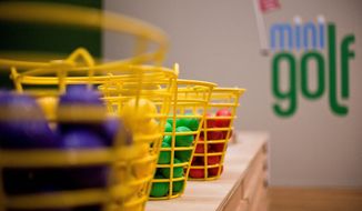 Colorful golf balls wait for players, who will find some of the holes of the National Building Museum’s 12-hole minigolf course deceptively difficult. One challenges golfers to aim for “par 40 instead of a par 4.” (Ryan M.L. Young/The Washington Times)