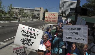 **FILE** Advocates demanding tougher gun control laws were among several dozen protesters who greeted President Obama outside the Oregon Convention Center in Portland, Ore., on July 24, 2012. Obama was in Oregon to raise money for his re-election campaign. (Associated Press)
