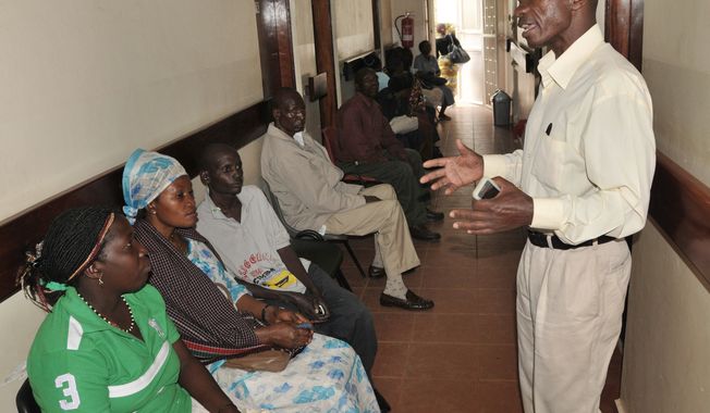 ** FILE ** In this Thursday, July 12, 2012, photo, a health worker from The AIDS Support Organization (TASO) health worker speaks with patients waiting for treatment in Kampala, Uganda. (AP Photo/Stephen Wandera)

