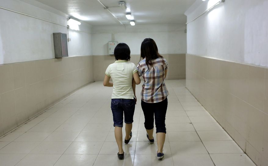 Dinh Thi Hong Loan, 30, (left) holds the hand of her girlfriend, Nguyen Thi Chi, 20, as they walk down a corridor in Hanoi. The lesbian couple have dated for more than two years and plan to marry. (Associated Press)