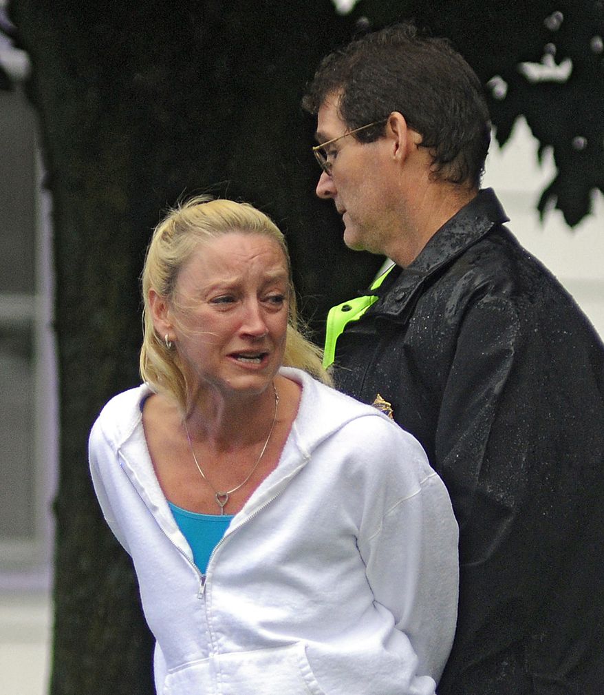 Kelleen Benway is detained July 28, 2012, by a police officer after she returned to her home in Oxford, Mass., where multiple shootings occurred. Daryl Benway, 41, who had recently separated from Kelleen, shot his two children, killing his 7-year-old daughter, before committing suicide, prosecutors said. Kelleen was later released. (Associated Press/Worcester Telegram & Gazette)