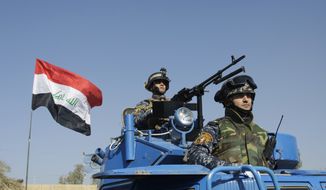 **FILE** The Iraqi flag waves Nov. 22, 2011, while federal police parade in Baghdad. (Associated Press)