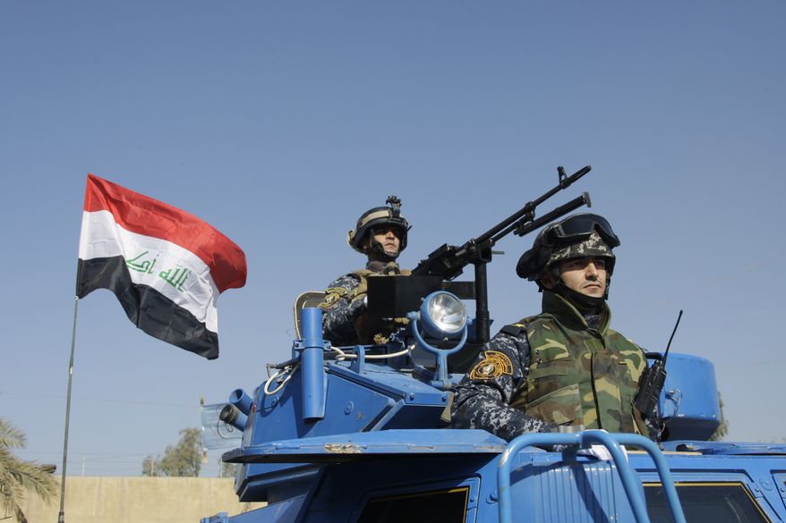 **FILE** The Iraqi flag waves Nov. 22, 2011, while federal police parade in Baghdad. (Associated Press)