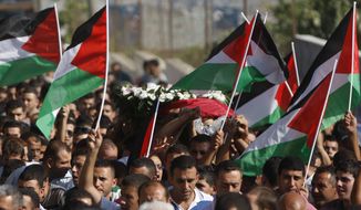 **FILE** Palestinian mourners carry the body of Akram Badr, 46, during his funeral July 31, 2012, in the village of Beitillu near in the West Bank city of Ramallah. Badr was killed the previous day at a checkpoint by the Israeli security forces near Jerusalem. (Associated Press)