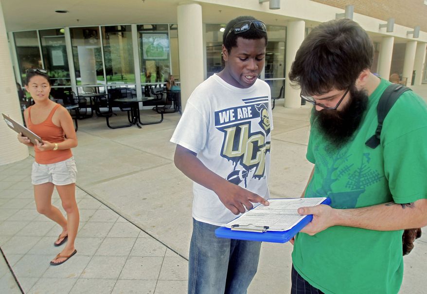 Aubrey Marks (left) looks on Tuesday at the University of Central Florida in Orlando, Fla., as Jordan Allen (center) helps student Casey Eirhstaedt register to vote. While most college campuses are relatively quiet, students at UCF have taken it upon themselves to register peers during the summer. (Associated Press)