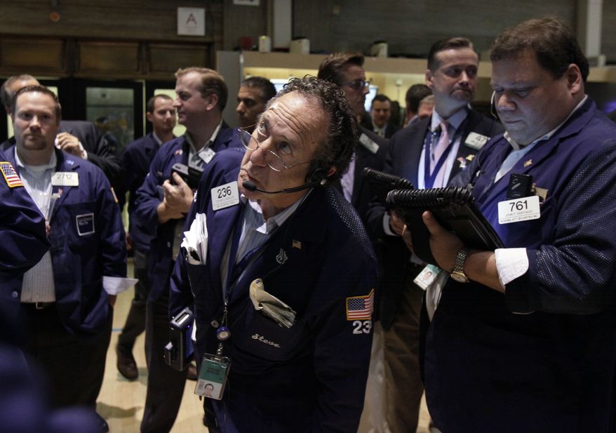 ** FILE ** In this Friday, Aug. 3, 2012, file photo, trader Steven Kaplan, center, checks prices as he waits for shares of AIG to resume trading on the floor of the New York Stock Exchange. The rating agency Standard & Poor’s stunned the world a year ago by stripping the U.S. government of its prized AAA bond rating. (AP Photo/Richard Drew, File)