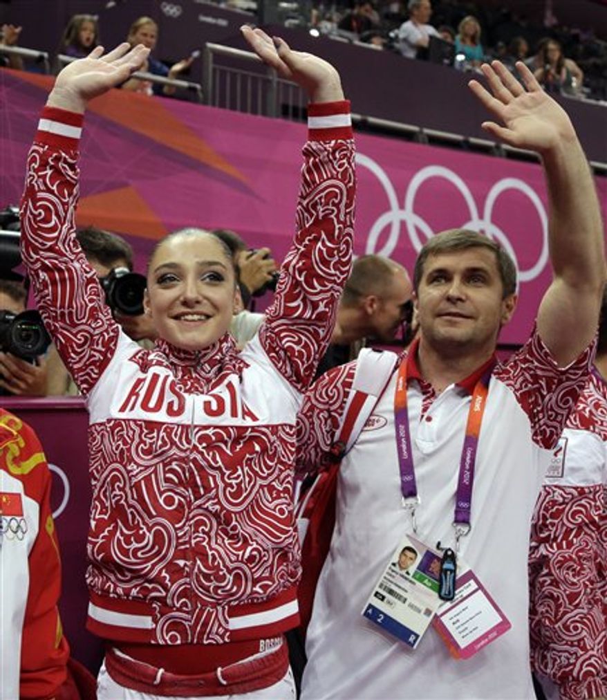 Russian gold medallist gymnast Aliya Mustafina, and coach Evgeny Grebenkin, right, wave to the crowd during the artistic gymnastics women's apparatus finals for the uneven bars at the 2012 Summer Olympics, Monday, Aug. 6, 2012, in London. (AP Photo/Julie Jacobson)