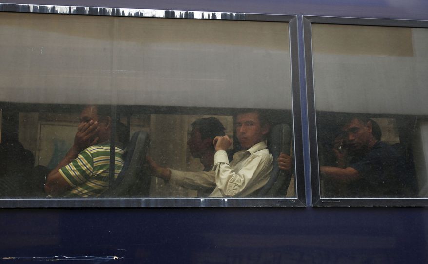 Migrants are seen on a police bus in central Athens on Aug. 5, 2012. Greek police say officers have begun an operation to arrest and deport illegal migrants from the center of the capital and along the country’s northeastern border. Over 100,000 illegal immigrants cross into Greece annually, most through Turkey. (Associated Press)