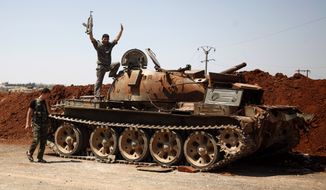 A Free Syria Army fighter waves Aug. 6, 2012, from the top of a destroyed army tank in the town of Anadan on the outskirts of Aleppo, Syria. (Associated Press)