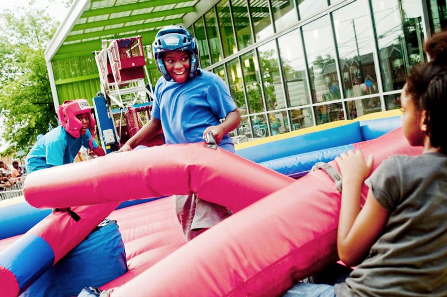 Michael Briscoe, 10, is loses his position during a jousting match at the Seven District's National Night Out at Anacostia Public Library on Tuesday, August 7, 2012, in Washington D.C. (Raymond Thompson/The Washington Times)