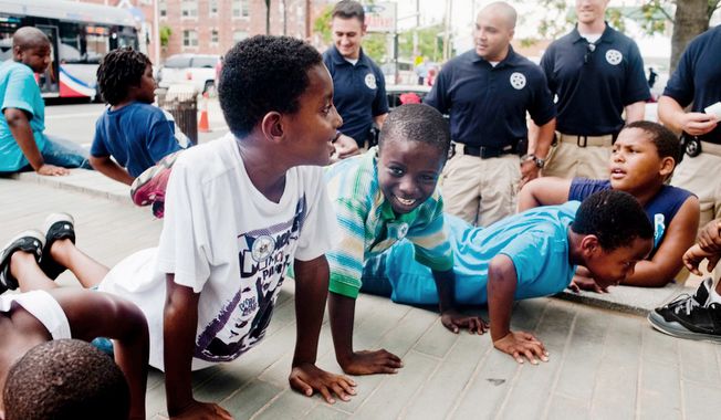 Mailk Brooks, 10 , Jeremiah Mikell, 9, and Devin Waters, 9, all from Washington D.C., do push ups for U.S. Marshals during the Seven District&#x27;s National Night Out.  (Raymond Thompson/The Washington Times)