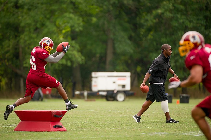 Washington Redskins defensive back Josh Wilson (26) runs a drill for Washington Redskins defensive back coach Raheem Morris, second from right, during afternoon practice at training camp at Redskins Park, Ashburn, Va., Tuesday, August 7, 2012. (Andrew Harnik/The Washington Times)