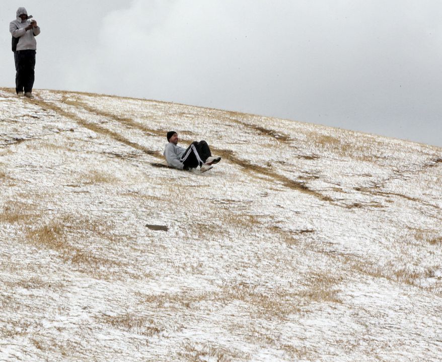 A man slides down a hill after a rare snowfall in Johannesburg on Tuesday sent people pouring out of their offices. The South African Weather Service said snow last fell in the city in June 2007. (Associated Press)