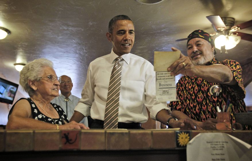 President Obama is shown an old photograph Aug. 9, 2012, at Romero's Cafe and Catering in Pueblo, Colo., by Robert Romero (right), the establishment's owner, and Virginia Romero (left), who founded the establishment. (Associated Press)