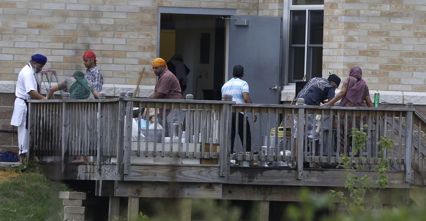 Members of the Sikh temple of Wisconsin in Oak Creek, Wis., wash items Aug. 9, 2012, as they return for the first time since a mass shooting at the temple four days earlier that claimed six members. (Associated Press)