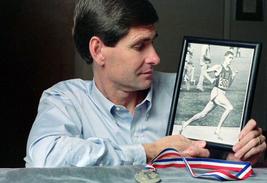At his home in Lawrence, Kan., in 1991, former Olympian Jim Ryun takes a look at a photograph taken of him at the Olympics in Mexico City in 1968, where he won a silver medal in the 1,500-meter run. (Associated Press)
