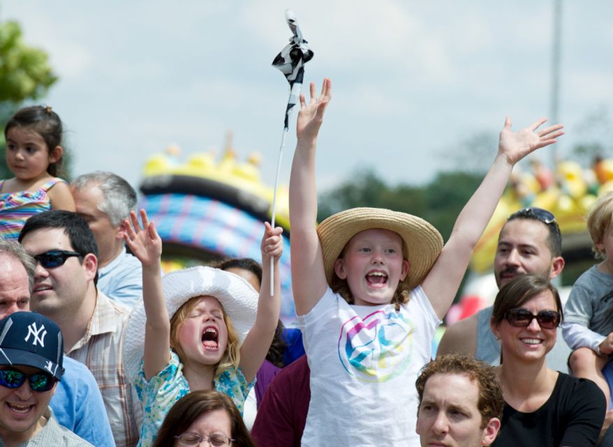 Sister Ellie (left), 6 and Hannah Holmes, 8, both from Arlington, raise their hands as they try to get selected to help out with the Sue Wee Flying Piglet Races at the Arlington County Fair. (Barbara L. Salisbury/The Washington Times)