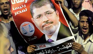 Thousands of supporters raise a poster of Egyptian President Mohammed Morsi as they celebrate in Cairo’s Tahrir Square late Sunday after Mr. Morsi retired the defense minister and chief of staff without the military’s objection. (Associated Press)