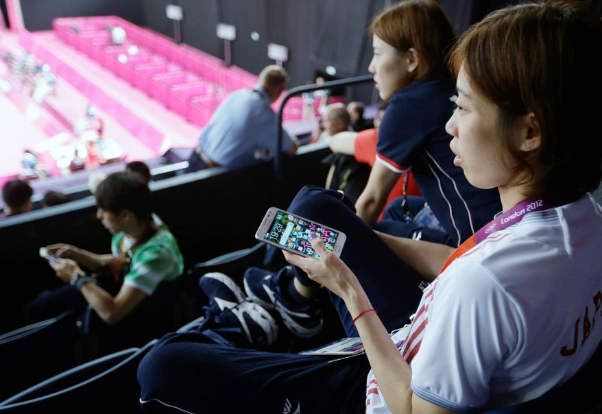 Japanese badminton player Satoko Suetsuna keeps her phone in hand while watch a badminton match in progress at the Olympic arena on July 31. In addition to social media increasing interest, NBC’s live streams inspired people who had never played videos on their tablets or smartphones to do so. Many watched events on more than one screen. (Associated Press)