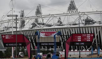 Workers adjust a sign outside the Olympic Stadium in London on Monday, Aug. 13, 2012, to prepare for the upcoming Paralympic Games. (AP Photo/Matt Dunham)
