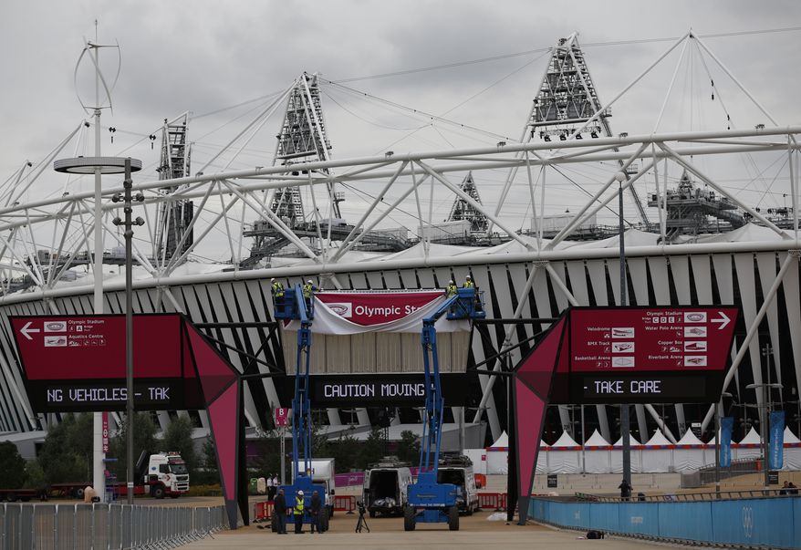 Workers adjust a sign outside the Olympic Stadium in London on Monday, Aug. 13, 2012, to prepare for the upcoming Paralympic Games. (AP Photo/Matt Dunham)