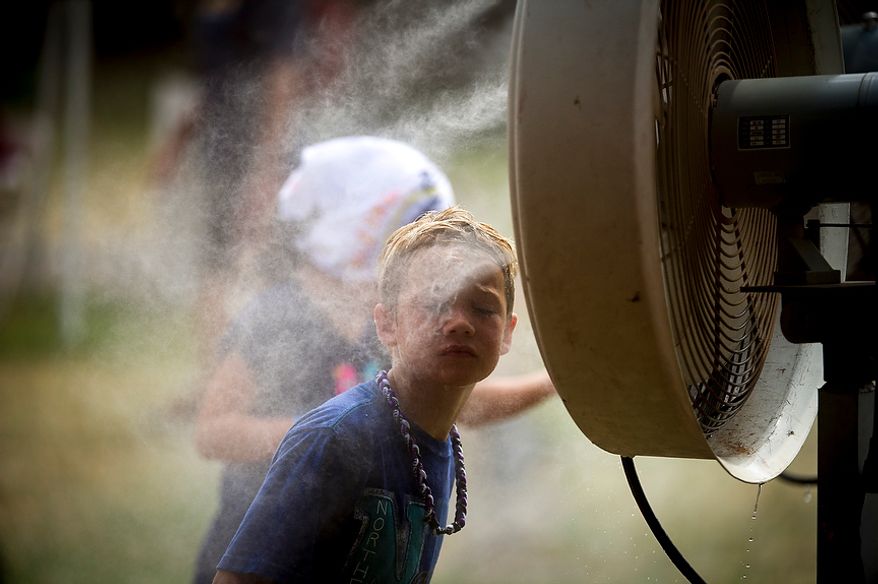 Adam Hopkins, 9, of Ashburn, Va., cools from the misting fan during the Redskins training camp at Redskins Park in Ashburn, Va., Tuesday, August 14, 2012. This is the last day that fans will be able to watch their team practice in this area. Next year the Redskins will move their practice facility to the Richmond, Va., area. (Rod Lamkey Jr./The Washington Times)