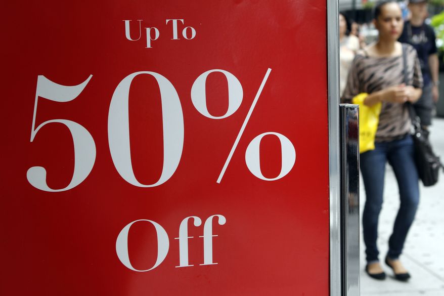 A shopper in New York passes a sign for discounted clothing on Thursday, July 19, 2012. (AP Photo/Fay Abuelgasim)