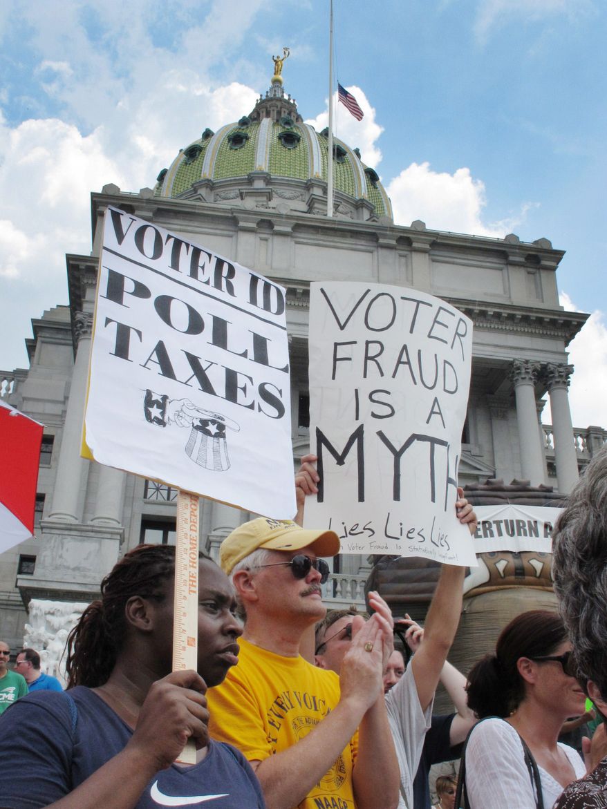 **FILE** Demonstrators hold signs July 24, 2012, at an NAACP-organized rally on the steps of the Pennsylvania Capitol in Harrisburg, Pa., to protest the state's new voter identification law. The law is being challenged in court as unconstitutional. Democrats say it's an election year stunt to steal the White House. Republicans say it's necessary to prevent voting fraud. (Associated Press)