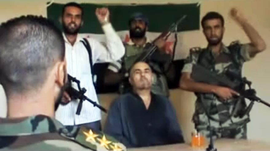 This image made from amateur video released by the Shaam News Network purports to show Syrian Pilot Col. Rafik Mohammed Suleiman being interrogated by a rebel officer Aug. 13, 2012, after his Soviet-made MiG warplane was apparently hit by ground fire over Deir el-Zour province, an area near the Iraqi border. (Associated Press/Shaam News Network)