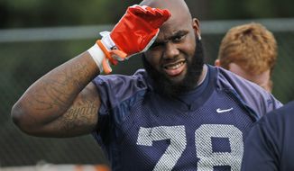 Virginia offensive tackle Morgan Moses (78) wipes his face during NCAA college practice in Charlottesville, Va., Monday, Aug. 6, 2012. (AP Photo/Steve Helber)