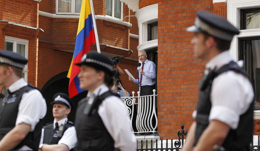 Surrounded by British police, WikiLeaks founder Julian Assange (center) makes a statement to the media and supporters from a window of Ecuadorean Embassy in central London on Sunday, Aug. 19, 2012. (AP Photo/Sang Tan)