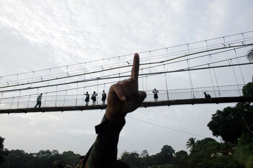 A Panama border police officer points as he begins to patrol in the Darien province, on the border with Colombia, in Yaviza, Panama. Panamanian authorities began noticing five years ago that the Darien Gap, the only interruption in the Pan-American Highway, was being used by migrant smugglers, usually to move people from Asia and Africa. (AP Photo/Arnulfo Franco)