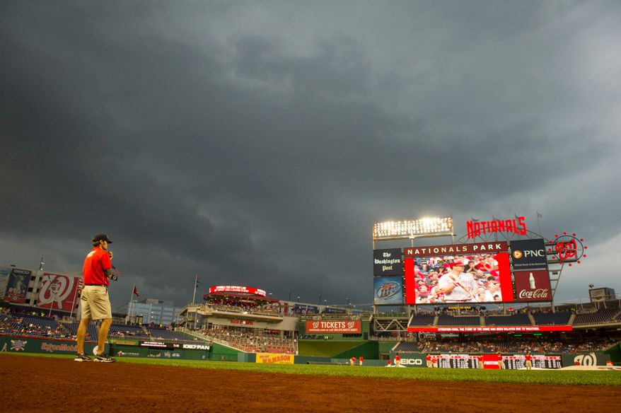 **FILE ** Assistant groundskeeper Mike Hrivnak keeps an eye on the approaching storm Aug. 20, 2012, during a rain delay in Washington, D.C. (Rod Lamkey Jr./The Washington Times)