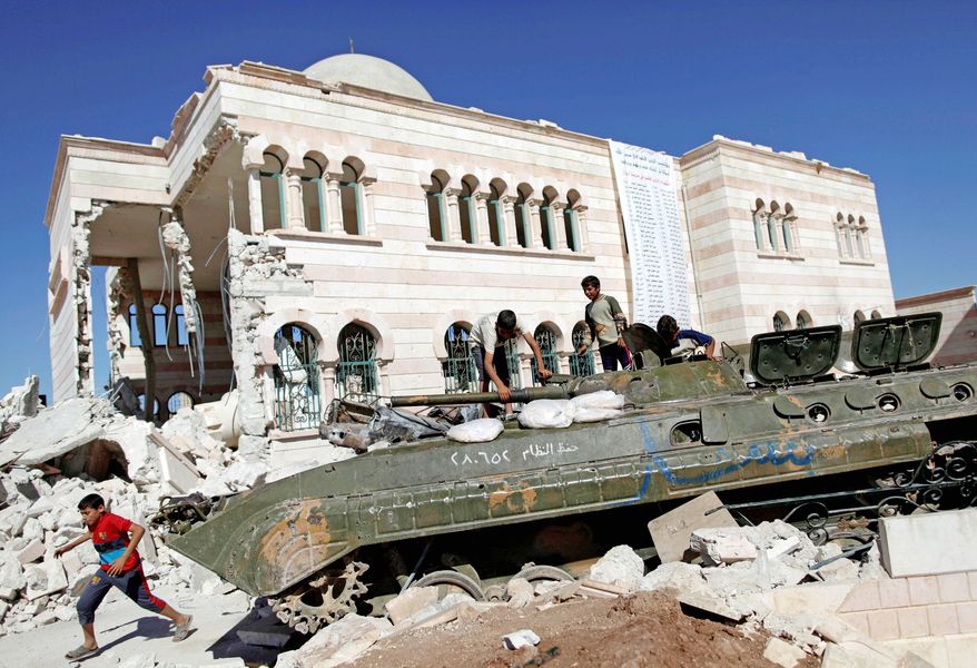 Syrian boys play on top of a destroyed military tank next to the rubble of a damaged mosque in the city of Azaz on the outskirts of Aleppo, Syria, on Wednesday. Government forces were engaged in a major battle for control of the northern city of Aleppo. (Associated Press)