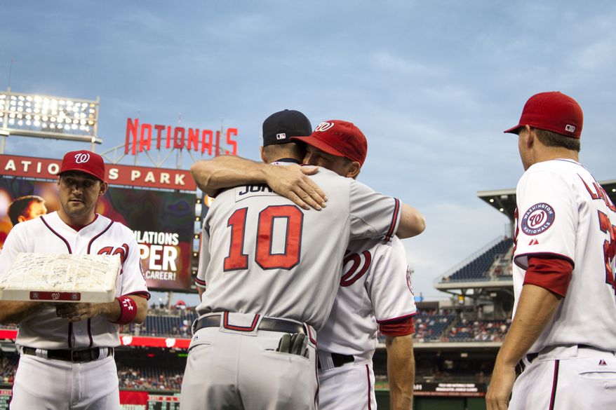Washington Nationals Mark DeRosa hugs Chipper Jones during a ceremony in his honor while Ryan Zimmerman holds a autographed base, left, and Adam LaRoche looks on Wednesday, Aug. 22, 2012, in Washington, DC. Jones said he would be retiring after this session. He has played his entire 19 year career was an Atlanta Brave, winning one World Series title with them in 1995. (Craig Bisacre/The Washington Times)