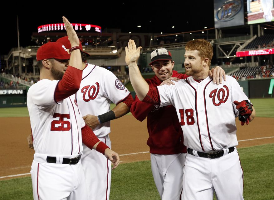 Washington Nationals' Chad Tracy, right, celebrates with Jesus Flores (26) and Sean Burnett, second from right, after Tracy reached first on a error scoring the winning run after a baseball game with the Atlanta Braves at Nationals Park on Tuesday, Aug. 21, 2012, in Washington. The Nationals won 5-4 in 13 innings. (AP Photo/Alex Brandon)