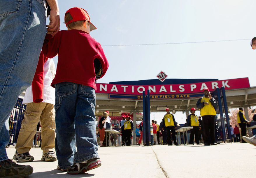 Fans have been flocking to Nationals Park this season, starting with Gavin Kearney, 4, holding the hand of his father, Gus, at the April 3 exhibition game against Boston. (Andrew Harnik/The Washington Times)