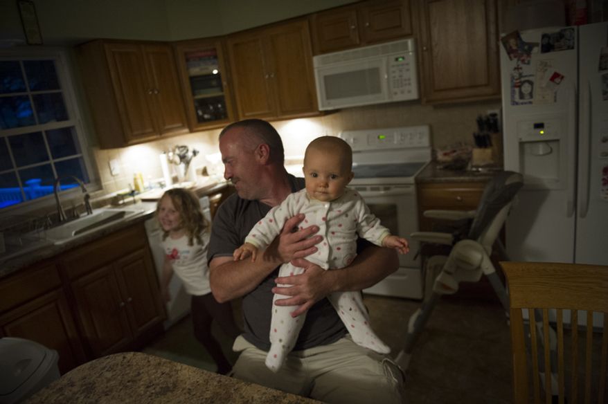 Joe Carr shares a light moment with his daughters Olivia, 8 months and Catalina, 5. Mr. Carr and his wife Sofia were at one point unemployed at the same time. Sofia has returned to paralegal work and Joe has returned to work at the same construction company that laid him off recently. (Rod Lamkey Jr./The Washington Times)