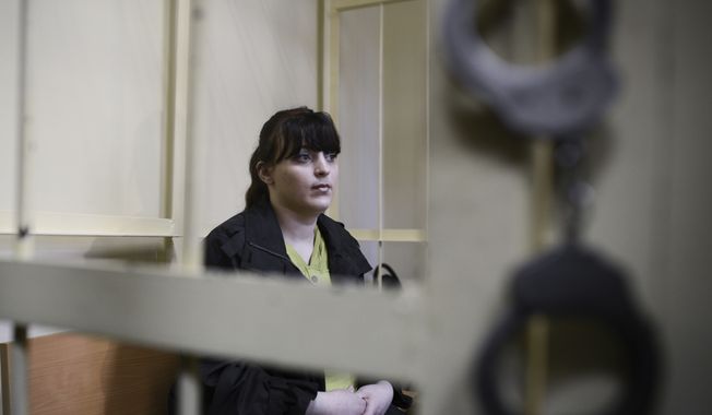 Russian opposition activist Taisiya Osipova sits in the defendant's cage in a courtroom in the western Russian city of Smolensk on Tuesday, Aug. 28, 2012. She was sentenced to eight years in prison on drug charges, her husband said, in a ruling that drew immediate opposition outrage. (AP Photo/Mitya Aleshkovskiy)