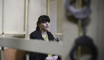 Russian opposition activist Taisiya Osipova sits in the defendant's cage in a courtroom in the western Russian city of Smolensk on Tuesday, Aug. 28, 2012. She was sentenced to eight years in prison on drug charges, her husband said, in a ruling that drew immediate opposition outrage. (AP Photo/Mitya Aleshkovskiy)