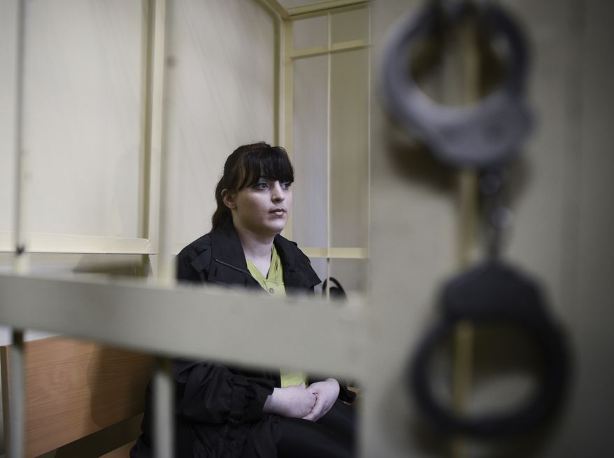 Russian opposition activist Taisiya Osipova sits in the defendant's cage in a courtroom in the western Russian city of Smolensk on Tuesday, Aug. 28, 2012. She was sentenced to eight years in prison on drug charges, her husband said, in a ruling that drew immediate opposition outrage. (AP Photo/Mitya Aleshkovskiy)