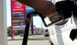 ** FILE ** In this August 2012 file photo, a driver in Kalamazoo, Mich., pumps gas near a sign showing a gallon of regular costing $4.09. (Associated Press)