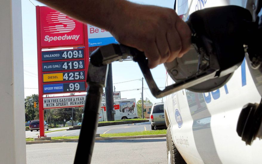 ** FILE ** In this August 2012 file photo, a driver in Kalamazoo, Mich., pumps gas near a sign showing a gallon of regular costing $4.09. (Associated Press)